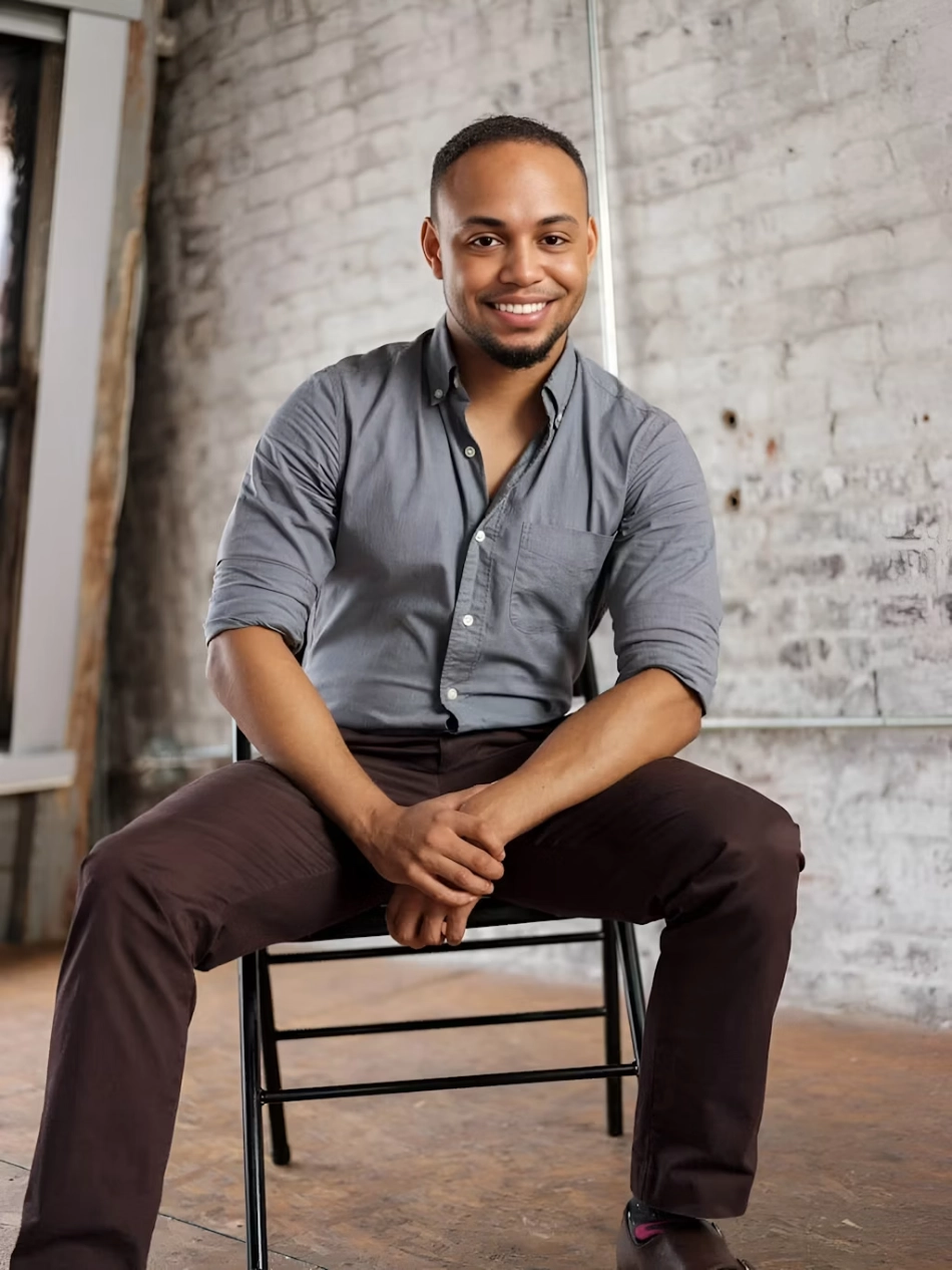 Portrait of a smiling man sitting against a brick wall